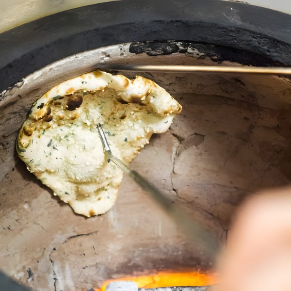 Naan bread baking inside a traditional tandoor oven at Mint Masala.