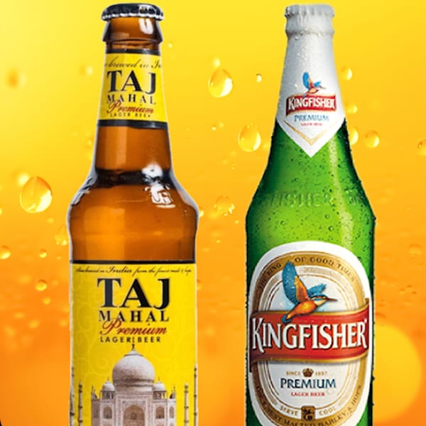 Two bottles of Indian beer, Taj Mahal and Kingfisher, with condensation on a yellow background.