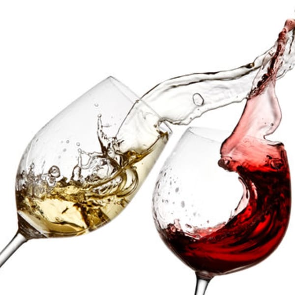 Red and white wine splashing between two wine glasses against a white background.